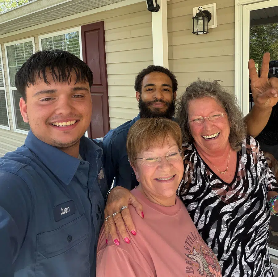 Smiling Prostar Services technicians with happy homeowners after HVAC service visit in the Wilson, NC area outside a residential home